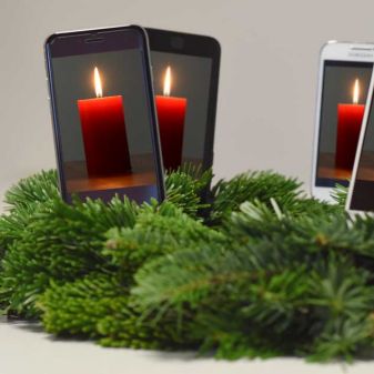 Handys in einem Kranz mit Kerzen, Kerzenkranz an Weihnachten mit Smartphones